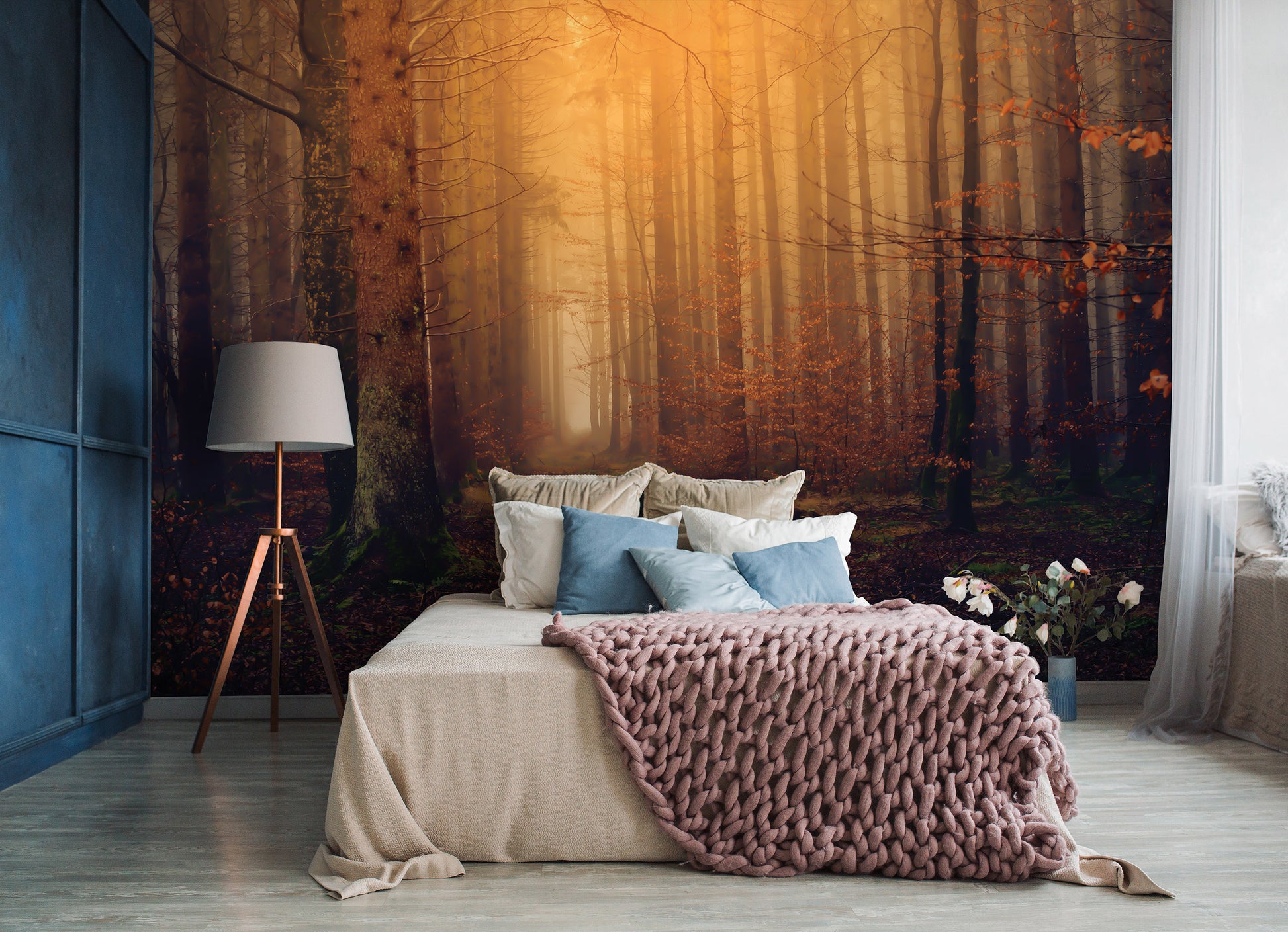 Cozy bedroom with a bed covered in pillows and a blanket, against a forest mural.