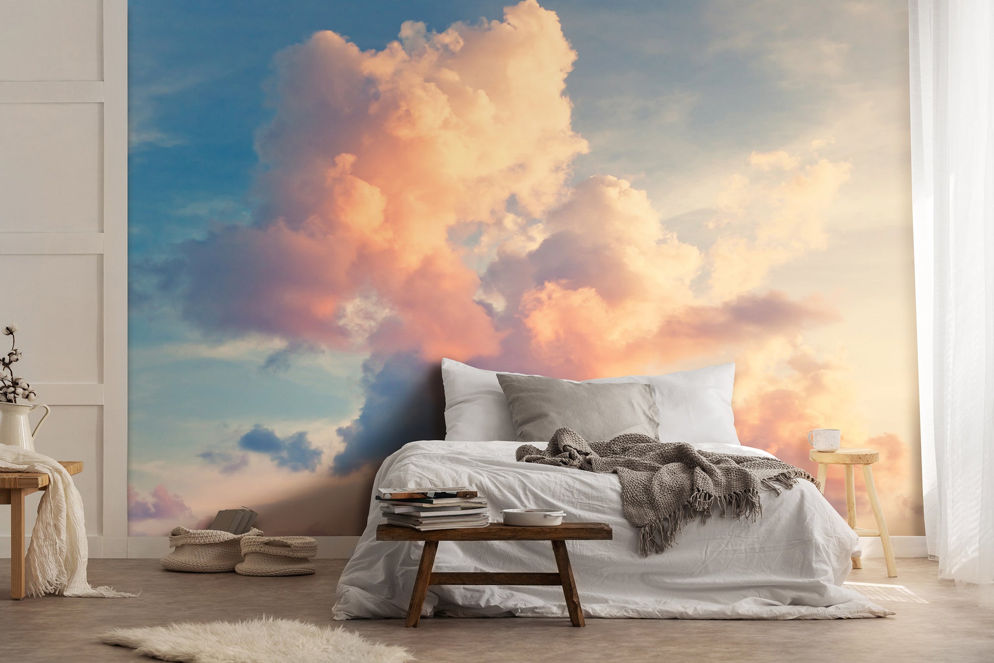 A nature-themed non-woven photo wallpaper featuring a cloudy sky view, installed on a wall above a bed and a wooden bench in a room with minimalist decor.