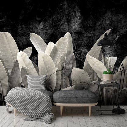 Gray armchair with ottoman and decorative plants against a dark wall.
