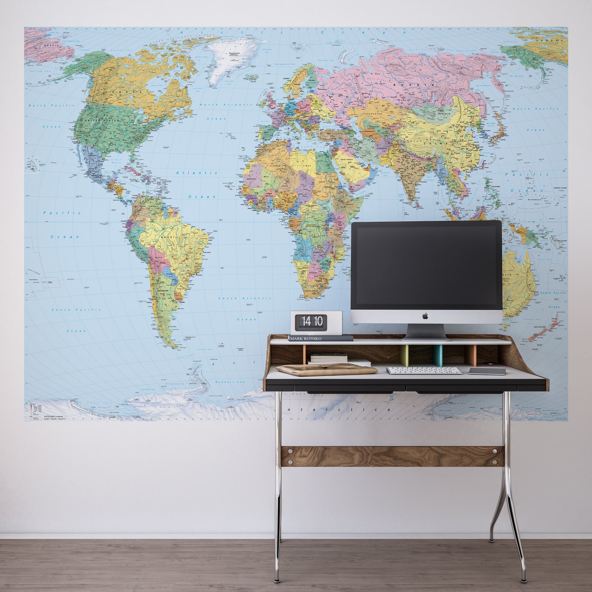 Desk with computer setup against a world map wall mural